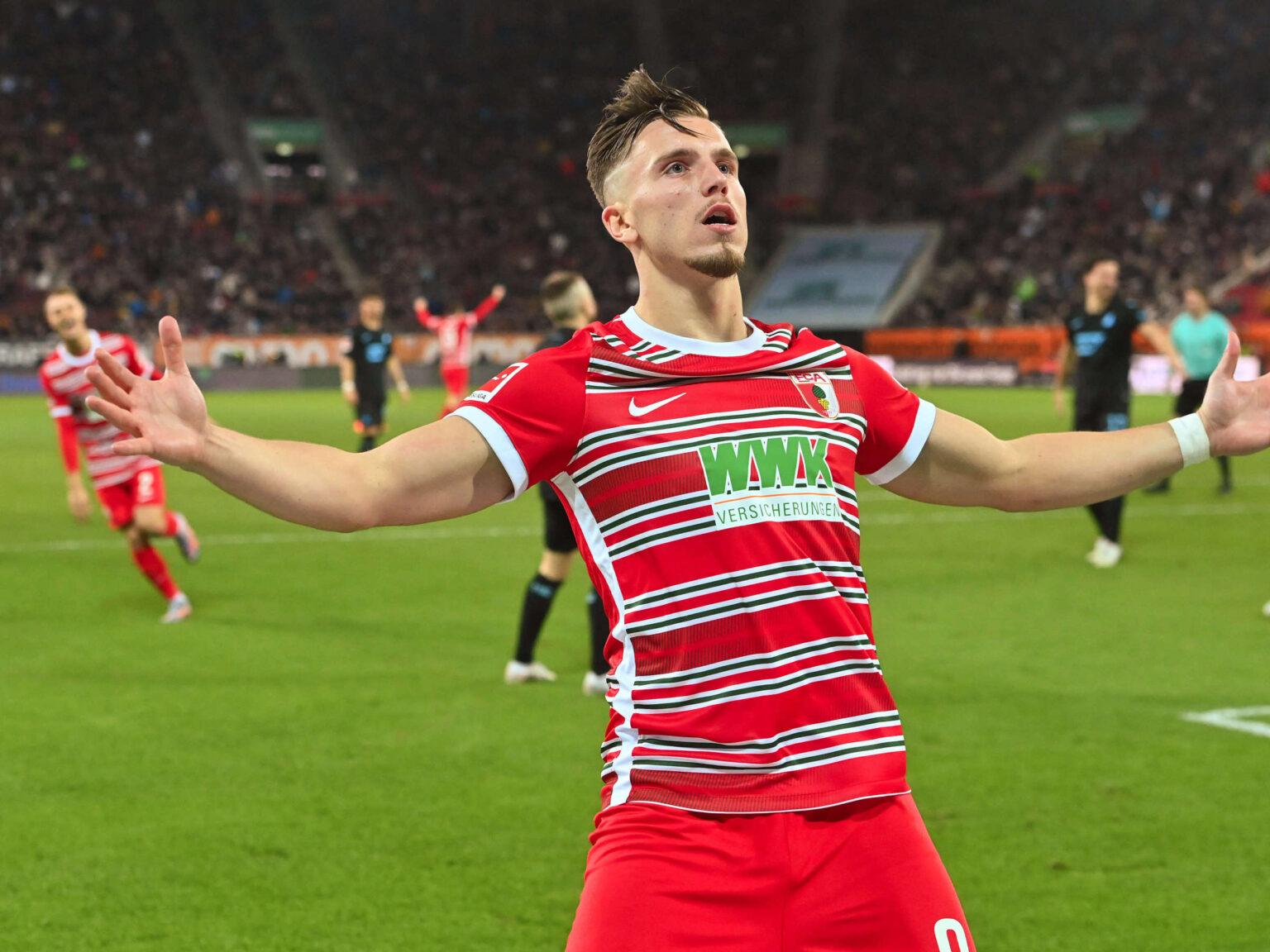 milan, demirovic esulta a braccia aperte con la maglia dell'Augsburg
